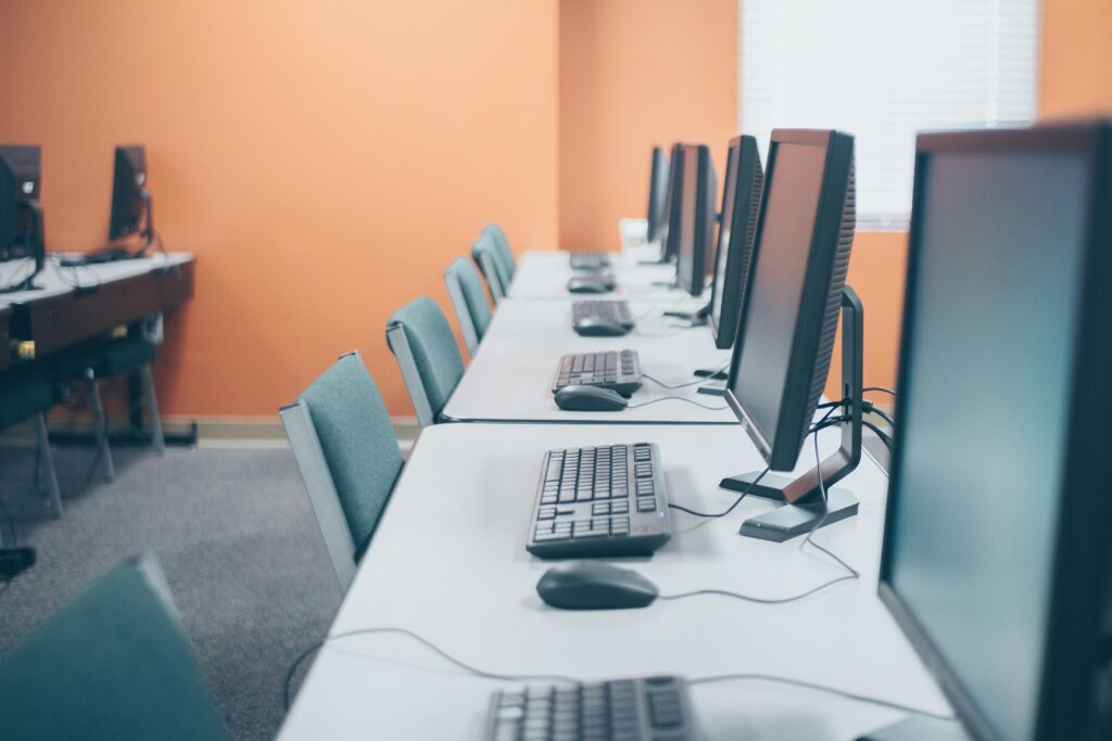 Contemporary style office with computers and keyboards near mouses on tables in light workspace